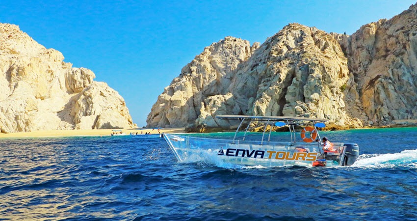 a boat in the water with Arch of Cabo San Lucas in the background